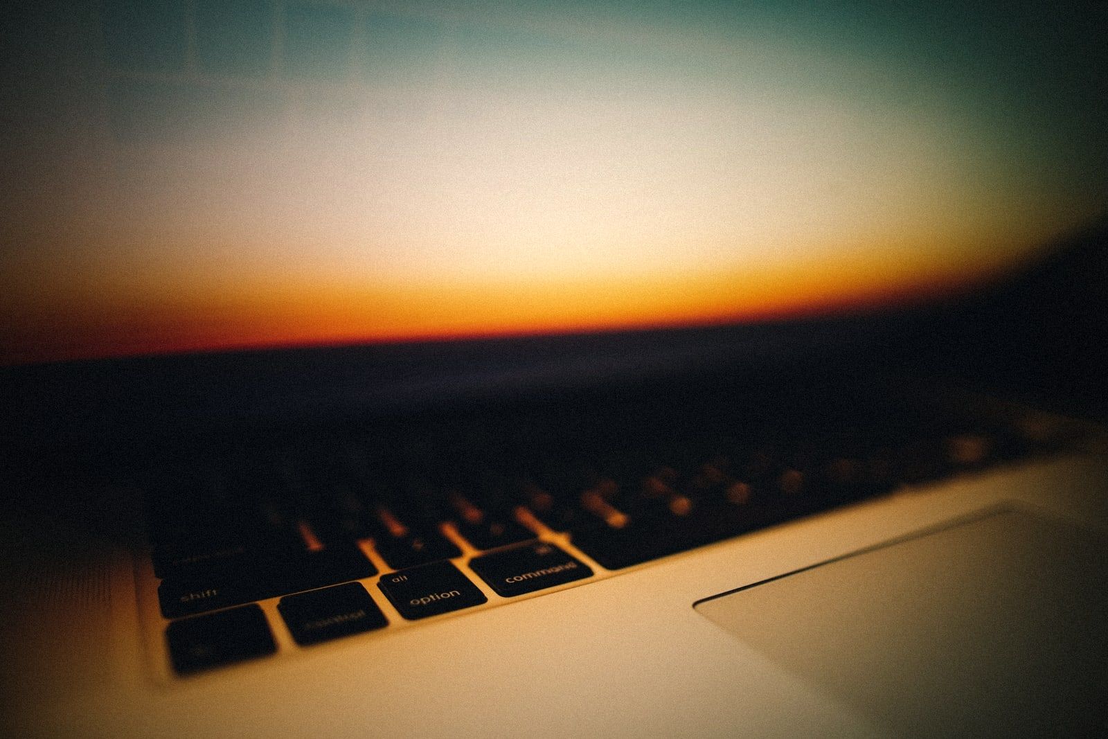 A keyboard close up, with a sunset behind it