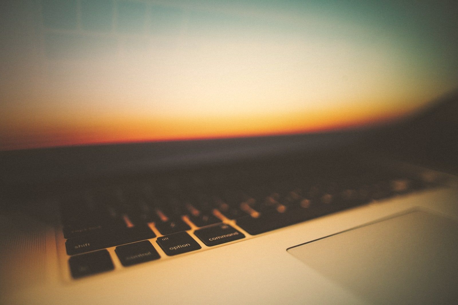 A keyboard close up, with a sunset behind it
