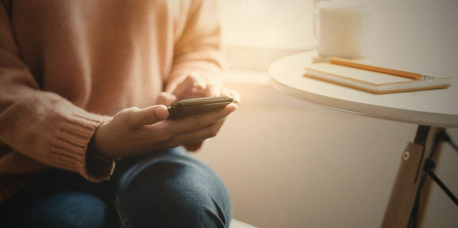 Hands holding a phone in soft window light